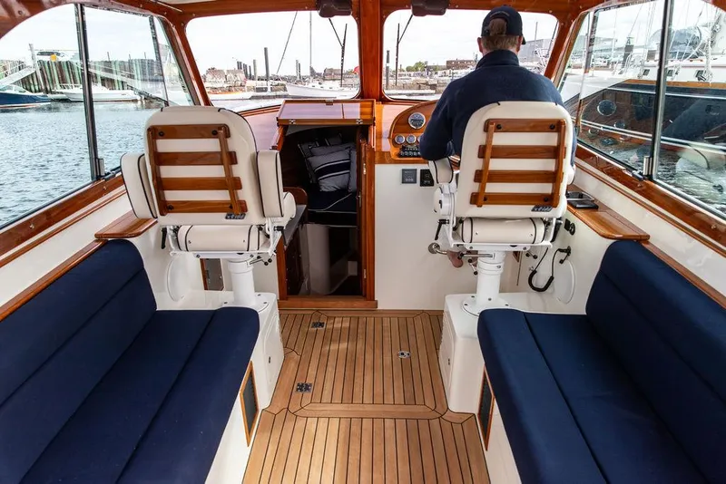 Slide: The Image of 2023 Hinckley Picnic Boat 34 S interior with wooden flooring and blue seating. - 10