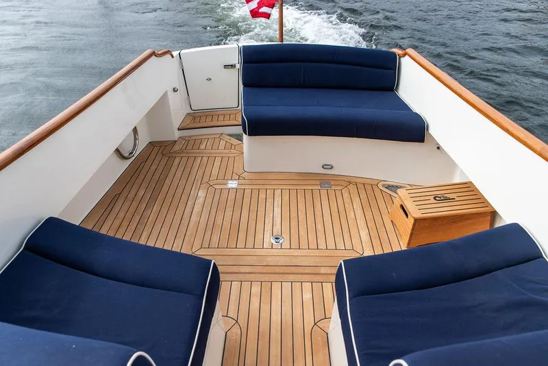 Slide: The Image of 2023 Hinckley Picnic Boat 34 S with teak deck and blue seating on open water. - 14