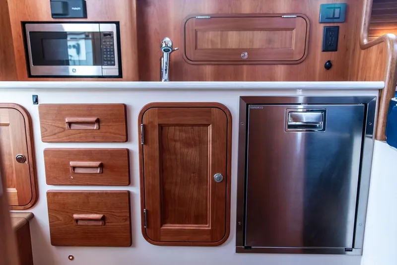 Slide: The Image of 2023 Hinckley Picnic Boat 34 S galley with wood cabinetry and stainless steel appliances. - 15