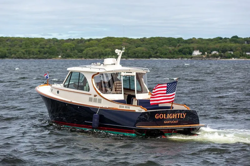 Slide: The Image of 2023 Hinckley Picnic Boat 34 S cruising on a lake with American flag. - 2