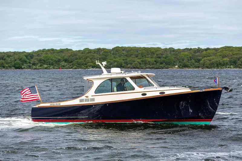 Slide: The Image of 2023 Hinckley Picnic Boat 34 S cruising on a lake with an American flag. - 21