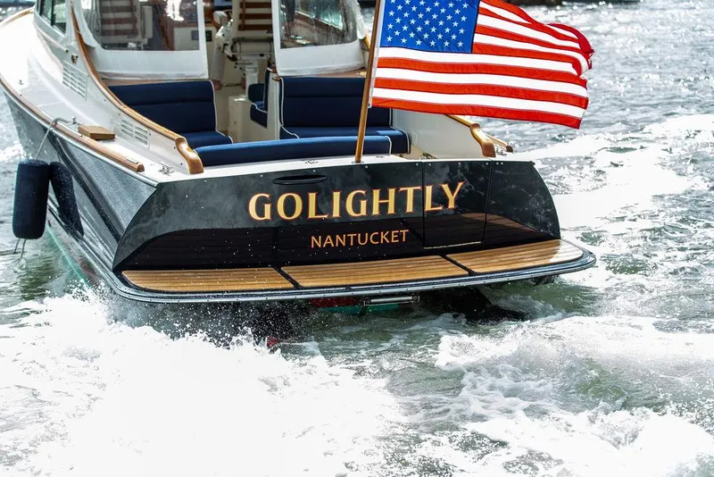 Slide: The Image of 2023 Hinckley Picnic Boat 34 S with American flag, named "Golightly," cruising in Nantucket waters. - 3