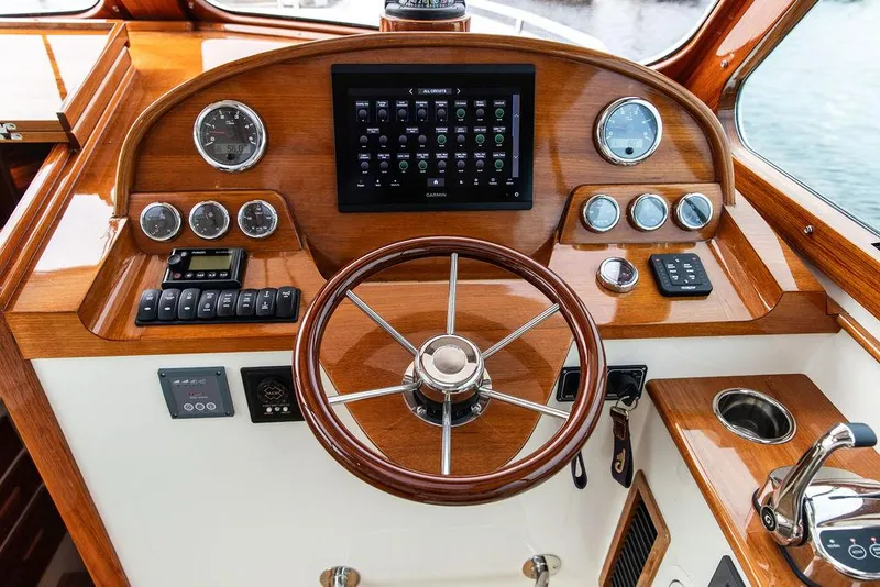 Slide: The Image of 2023 Hinckley Picnic Boat 34 S helm with wooden steering wheel and modern controls. - 6