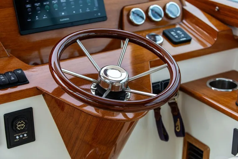 Slide: The Image of 2023 Hinckley Picnic Boat 34 S helm with wooden steering wheel and modern controls. - 7