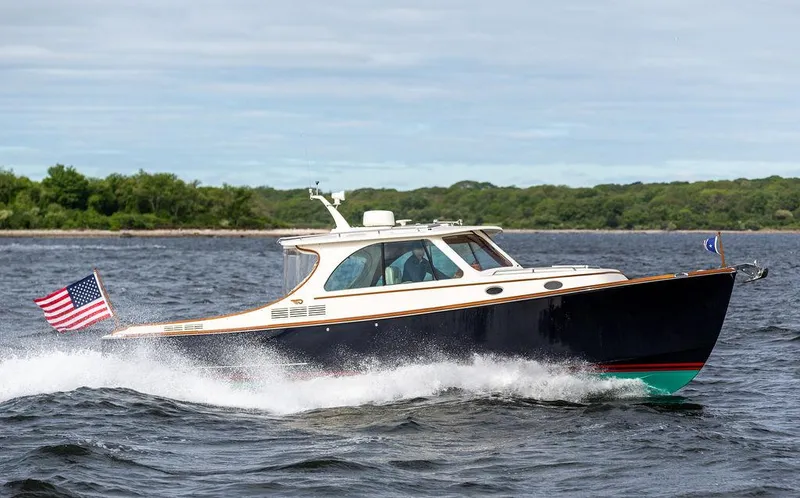Slide: The Image of 2023 Hinckley Picnic Boat 34 S cruising on open water with American flag. - 23