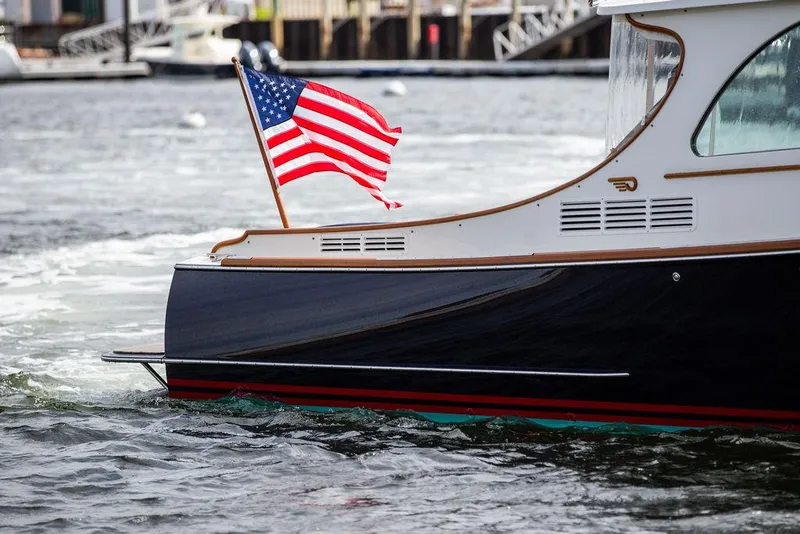 Slide: The Image of 2023 Hinckley Picnic Boat 34 S with American flag on water. - 24