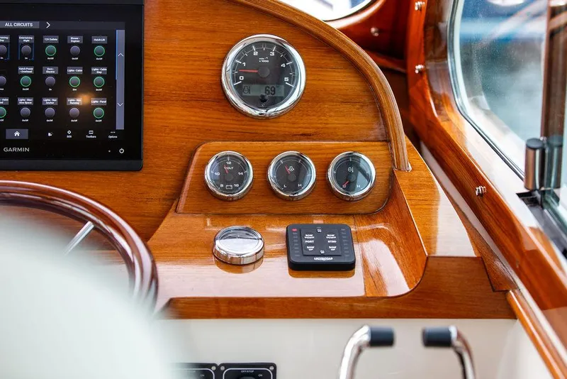 Slide: The Image of 2023 Hinckley Picnic Boat 34 S dashboard with gauges and controls, featuring wood finish. - 9