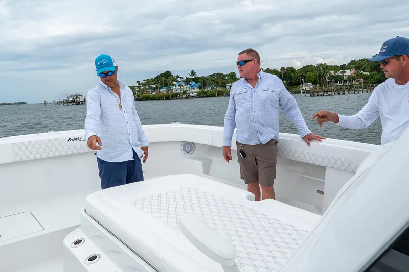 Slide: The Image of Three people on a 2026 Front Runner 37 Catamaran, discussing features on deck. - 17