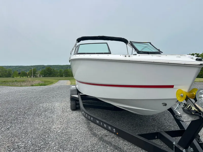 The Image of 2025 Four Winns H2 Freedom boat on trailer, parked on gravel with scenic background. - 1