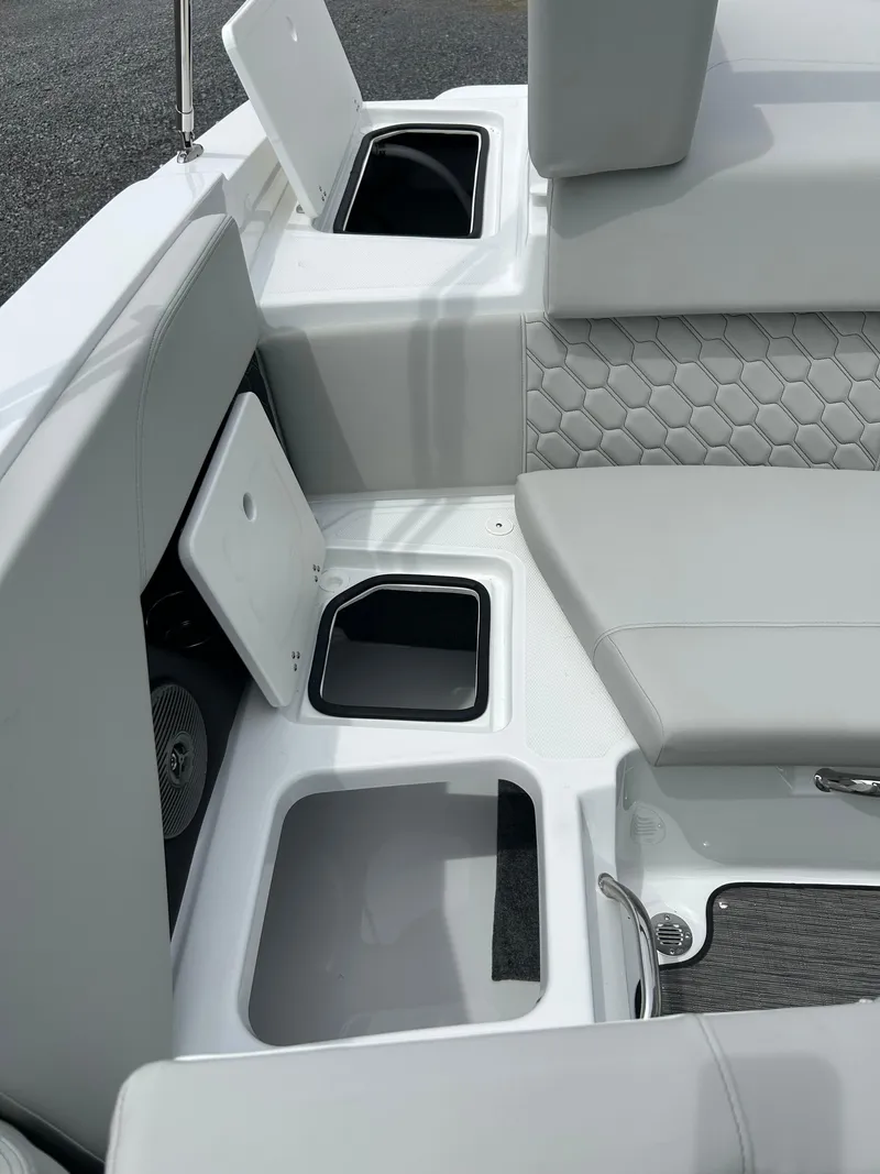 Slide: The Image of 2025 Four Winns H2 Freedom boat interior with open storage compartments and cushioned seating. - 14