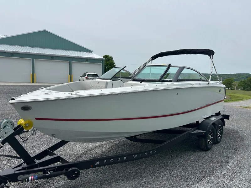 Slide: The Image of 2025 Four Winns H2 Freedom boat on trailer, parked outdoors near a building. - 3