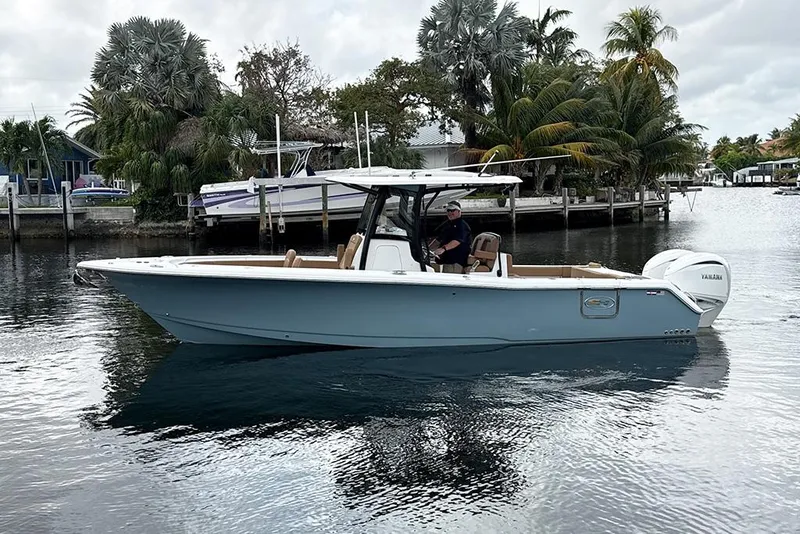 The Image of 2023 Sea Hunt Gamefish 30 boat on calm water, surrounded by tropical trees. - 0