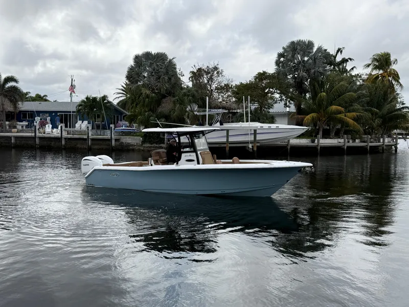 Slide: The Image of 2023 Sea Hunt Gamefish 30 boat on calm water near a dock with palm trees. - 29