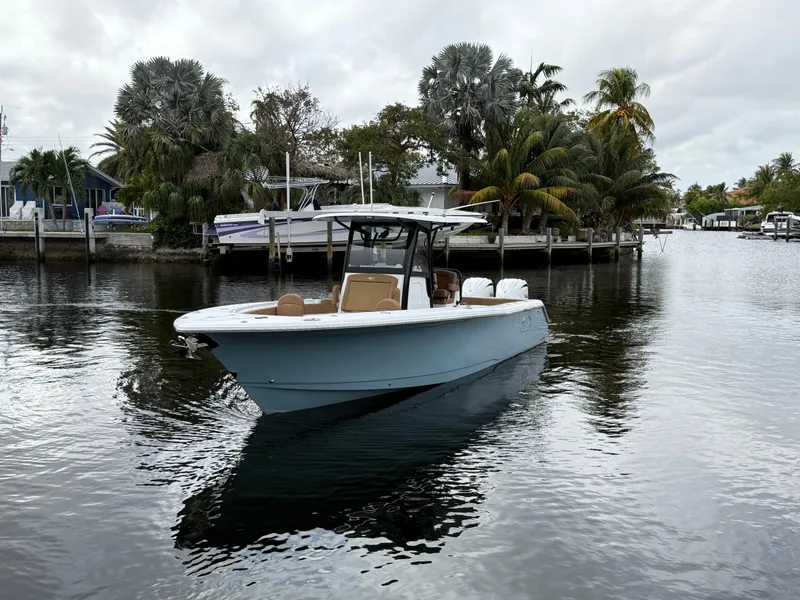 Slide: The Image of 2023 Sea Hunt Gamefish 30 boat on calm water, surrounded by tropical trees. - 32