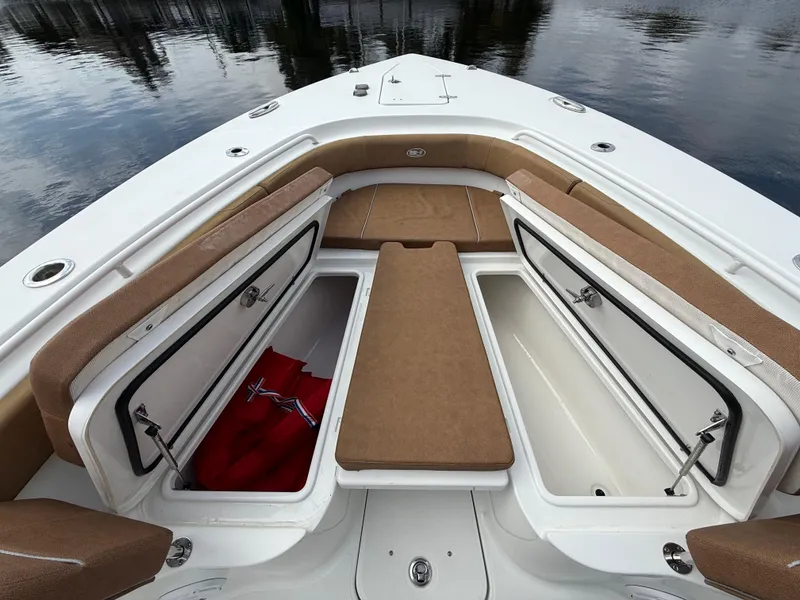 Slide: The Image of 2023 Sea Hunt Gamefish 30 Forward Seating with open storage compartments on a calm water backdrop. - 4