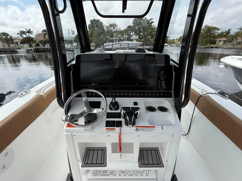 Slide: The Image of 2023 Sea Hunt Gamefish 30 helm with modern controls and scenic waterfront view. - 9