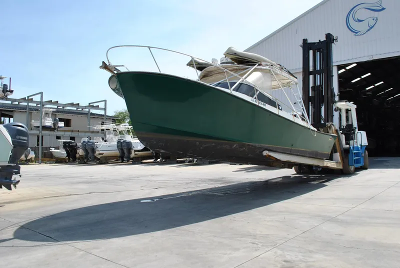 Slide: The Image of 1987 Halter 31 Lafitte Skiff boat lifted by forklift near a warehouse. - 7