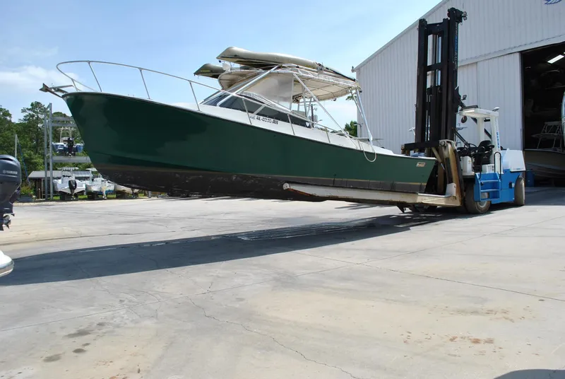 Slide: The Image of 1987 Halter 31 Lafitte Skiff boat lifted by forklift near a warehouse. - 9