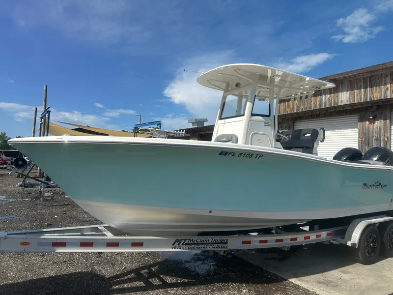 The Image of 2023 NauticStar 2602 Legacy boat on trailer, parked outdoors under blue sky. - 1