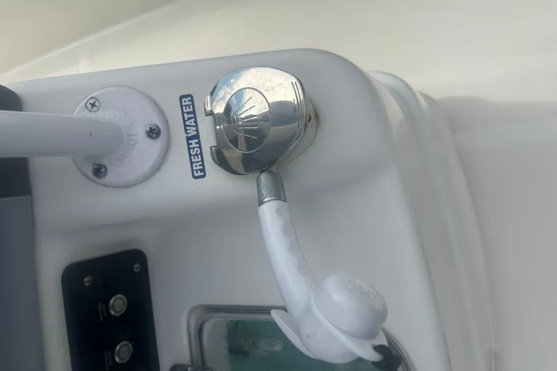 Slide: The Image of Freshwater outlet on 2023 NauticStar 2602 Legacy boat, featuring chrome and white fixtures. - 43