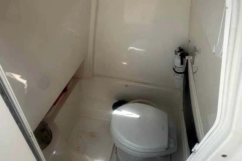 Slide: The Image of Interior of 2023 NauticStar 2602 Legacy boat, featuring a compact marine toilet. - 47