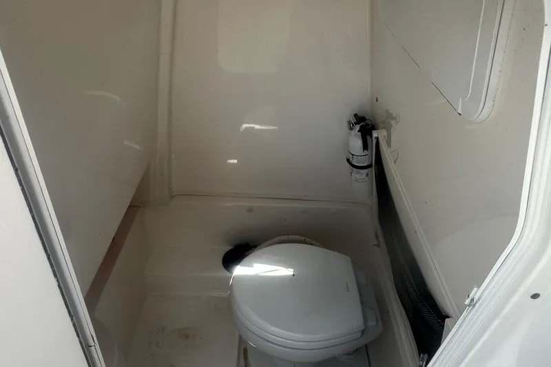 Slide: The Image of 2023 NauticStar 2602 Legacy boat interior with toilet and fire extinguisher. - 48