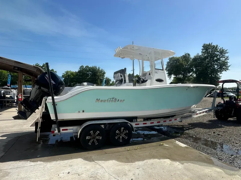 Slide: The Image of 2023 NauticStar 2602 Legacy boat on trailer, parked outdoors under clear blue sky. - 6