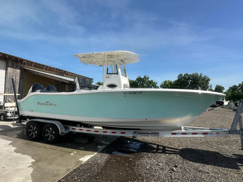 Slide: The Image of 2023 NauticStar 2602 Legacy boat on trailer, parked outdoors under clear sky. - 7