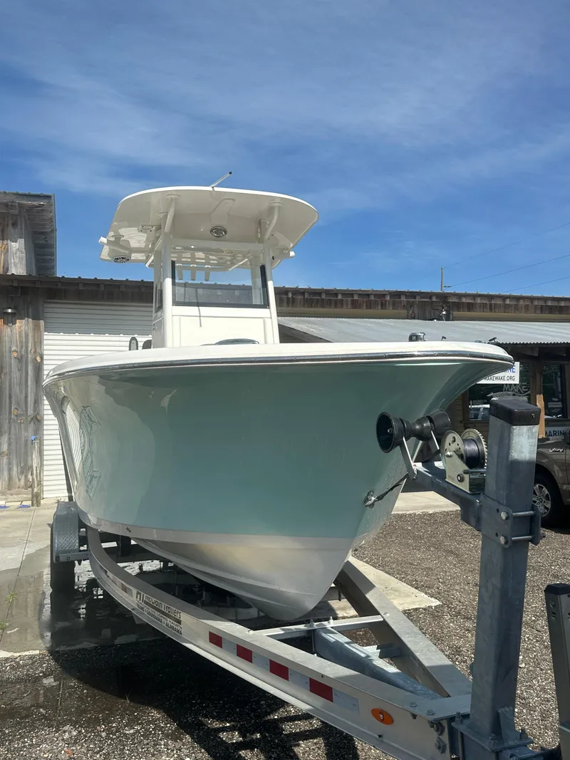 Slide: The Image of 2023 NauticStar 2602 Legacy boat on trailer, displayed outdoors under clear blue sky. - 9