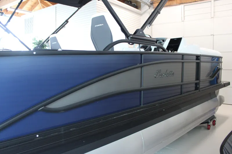 Slide: The Image of 2025 Barletta Corsa 23UC pontoon boat, blue and gray exterior, in a showroom setting. - 12