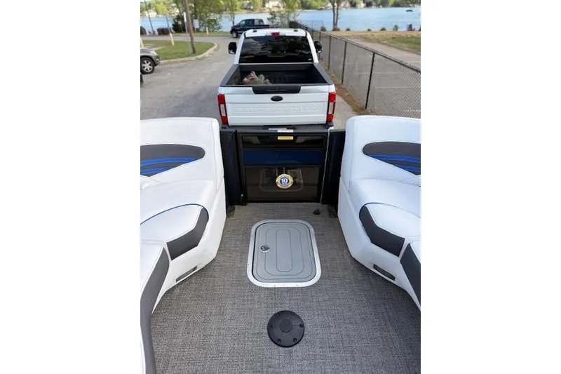 Slide: The Image of 2025 Barletta Corsa 23UC pontoon boat interior with truck in background near lake. - 25