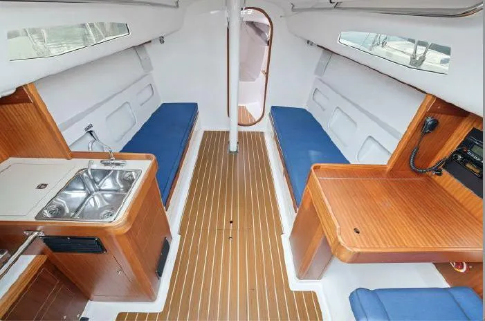 Slide: The Image of 2013 J Boats J/111 interior with wood finish, blue seating, and compact kitchen area. - 11