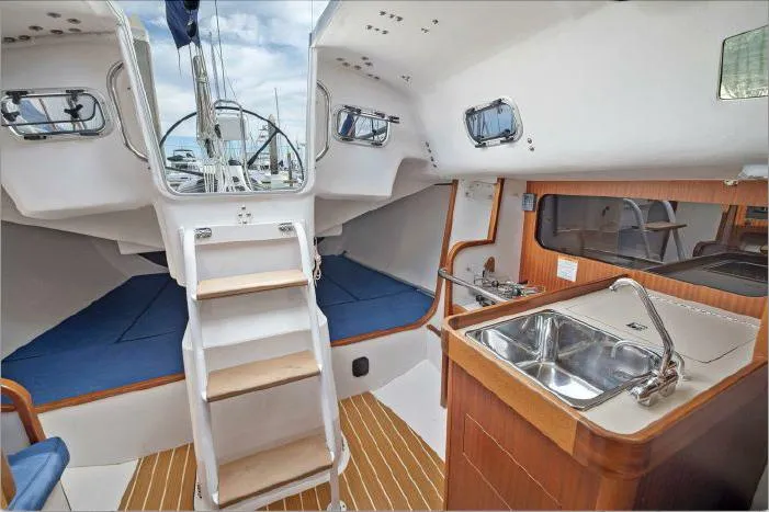 Slide: The Image of Interior of 2013 J Boats J/111 sailboat with wooden flooring and compact kitchen area. - 12