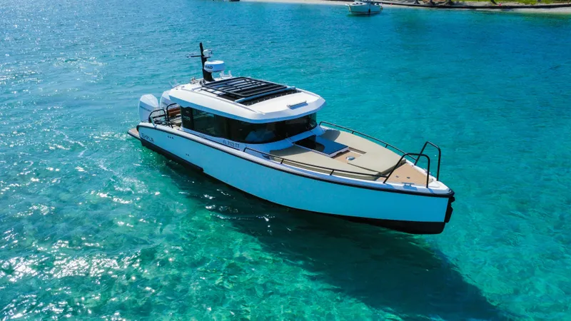 Slide: The Image of 2024 XO Boats EXPLR 10S Plus cruising on clear turquoise waters. - 0