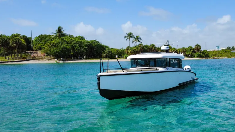 Slide: The Image of 2024 XO Boats EXPLR 10S Plus cruising in clear turquoise waters near a tropical island. - 10