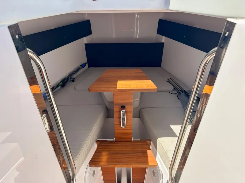 Slide: The Image of 2024 XO Boats EXPLR 10 Sport Plus cabin interior with wooden table and seating. - 13