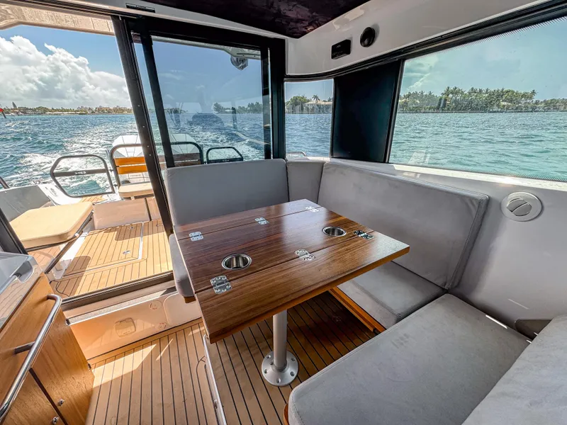 Slide: The Image of 2024 XO Boats EXPLR 10S Plus interior with wooden table and seating, overlooking water. - 18