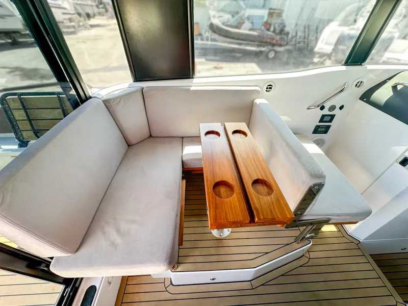 Slide: The Image of 2024 XO Boats EXPLR 10 Sport Plus interior with cushioned seating and wooden table. - 19