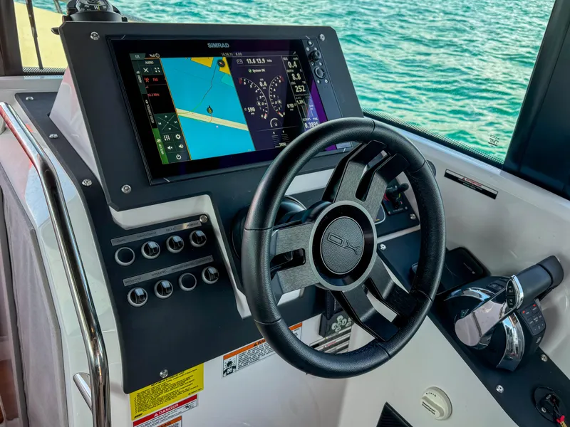Slide: The Image of 2024 XO Boats EXPLR 10S Plus helm with navigation display and steering wheel. - 22
