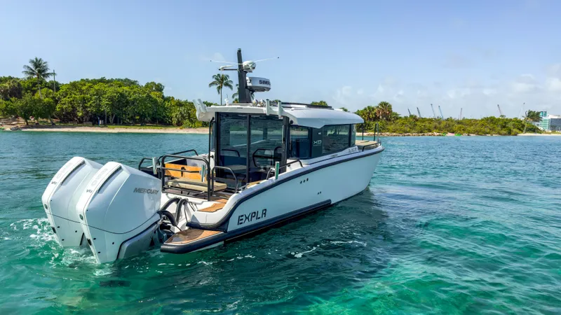 Slide: The Image of 2024 XO Boats EXPLR 10S Plus cruising on clear blue water near a tropical shoreline. - 3