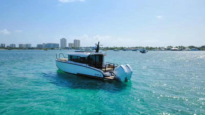 Slide: The Image of 2024 XO Boats EXPLR 10S Plus cruising on clear blue water near a city skyline. - 33