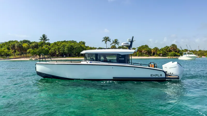 Slide: The Image of 2024 XO Boats EXPLR 10S Plus cruising on clear blue water near a tropical shoreline. - 36