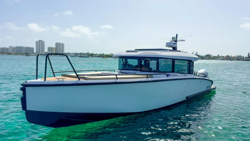 Slide: The Image of 2024 XO Boats EXPLR 10S Plus on clear blue water, city skyline in background. - 37