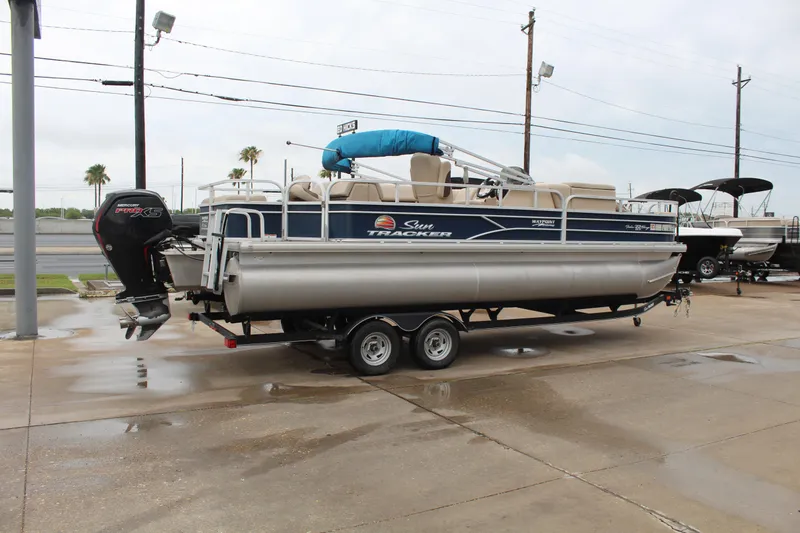 Slide: The Image of 2019 Sun Tracker Fishin' Barge 22 DLX pontoon boat on trailer, parked outdoors. - 5