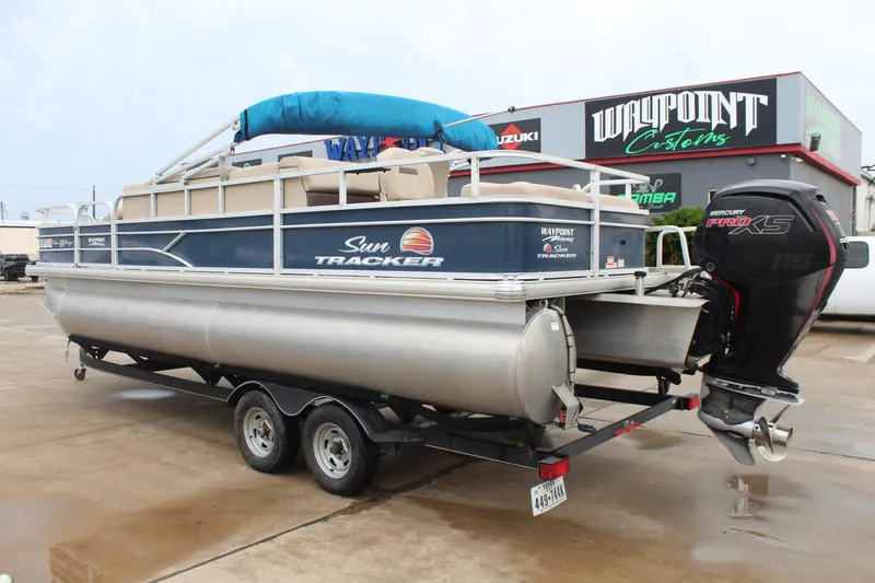 Slide: The Image of 2019 Sun Tracker Fishin' Barge 22 DLX pontoon boat on trailer, parked outside dealership. - 7