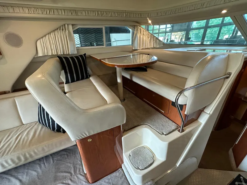 Slide: The Image of Interior of 1999 Sea Ray 400 Sedanbridge with plush seating and dining area. - 10