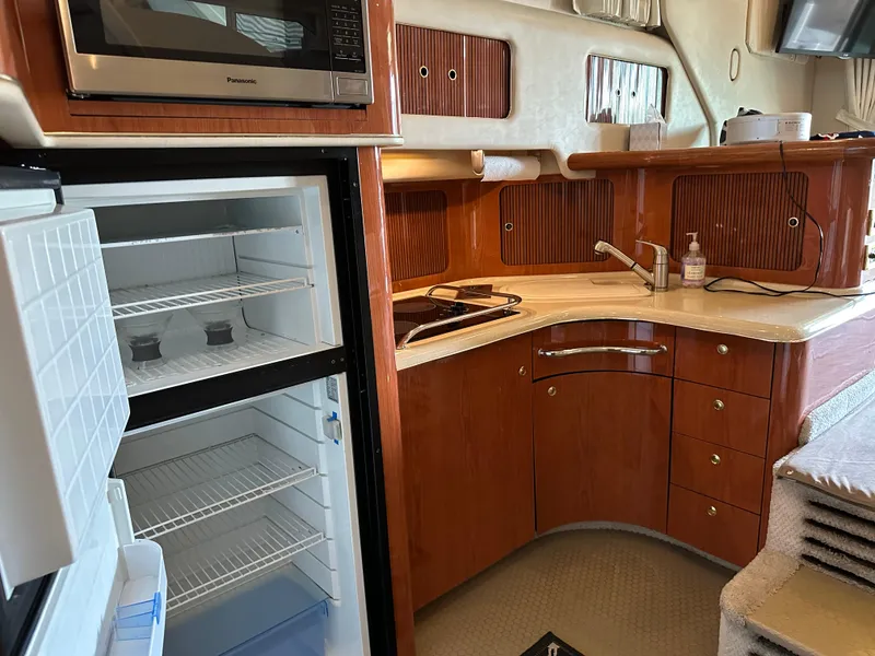 Slide: The Image of 1999 Sea Ray 400 Sedanbridge kitchen with open fridge, microwave, and wooden cabinetry. - 13