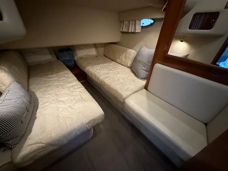 Slide: The Image of 1999 Sea Ray 400 Sedanbridge cabin interior with beige seating and striped pillows. - 19