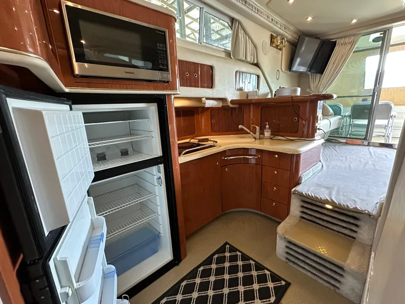 Slide: The Image of 1999 Sea Ray 400 Sedanbridge yacht interior with kitchen, open fridge, and microwave. - 2