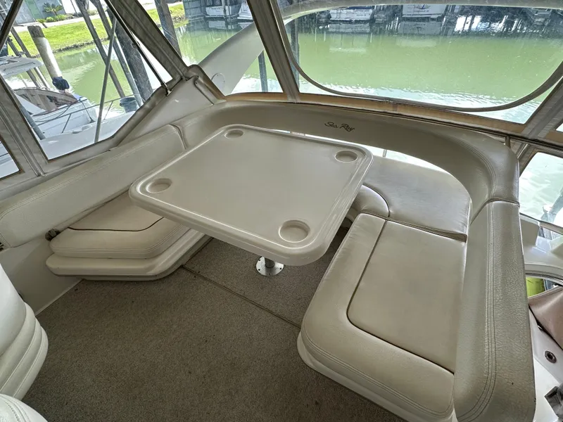 Slide: The Image of 1999 Sea Ray 400 Sedanbridge interior with cushioned seating and table, overlooking water. - 28